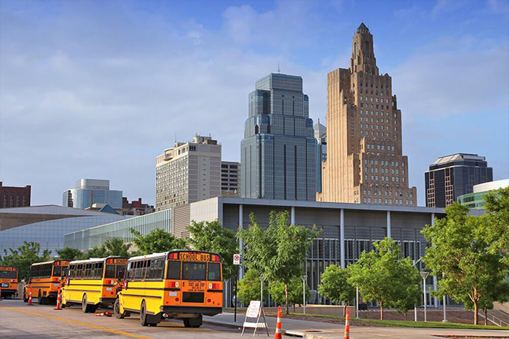 Three school buses with Kansas City skyline in background
