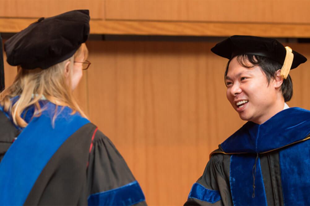 Two people in caps and gowns shaking hands