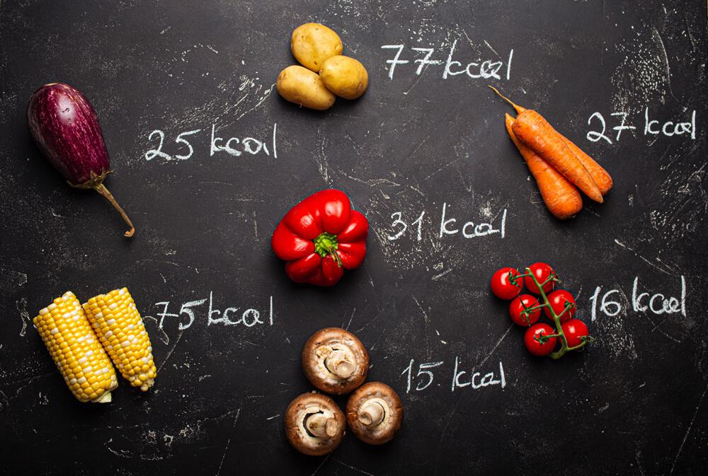Vegetables on display with their kcal count written in chalk