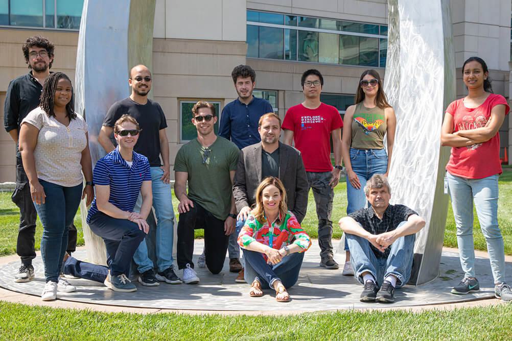 Dr. Nicolas Rohner's lab team standing beneath a statue at the Stowers Institute in Kansas City