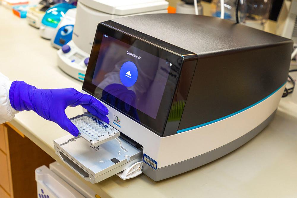 A researcher loading a cartridge in to the 10X Genomics Chromium iX instrument