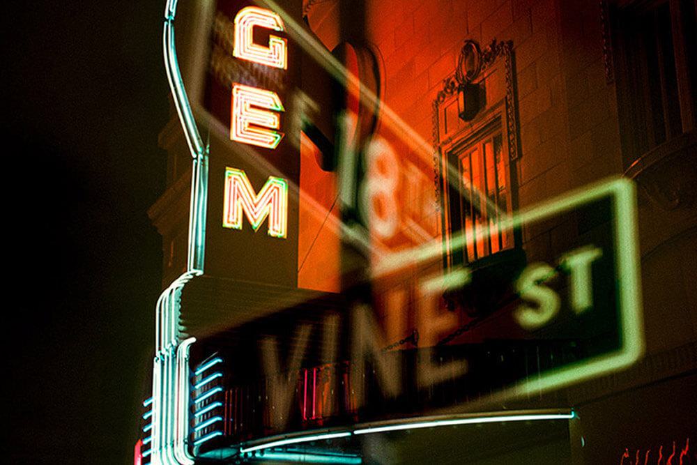 Neon building sign "Gem" with an overlapping view of intersection street signs "E 18th & Vine St"
