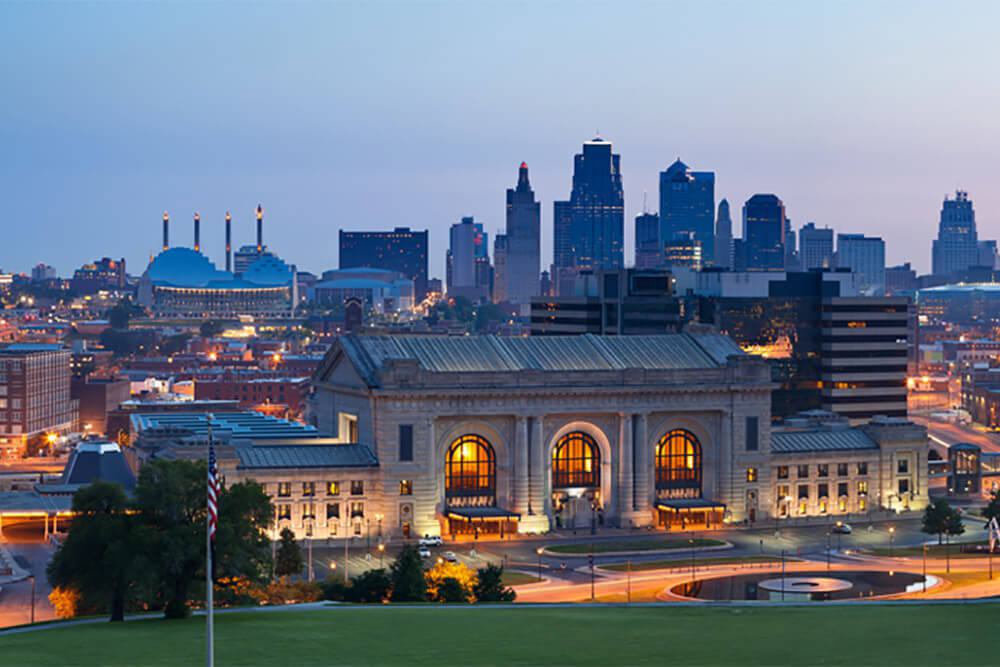 Kansas City skyline with Stowers building in foreground illuminated at dusk