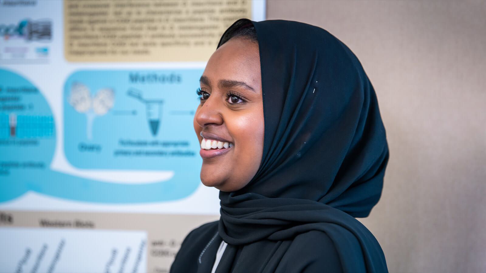 Side view of woman smiling in front of science poster