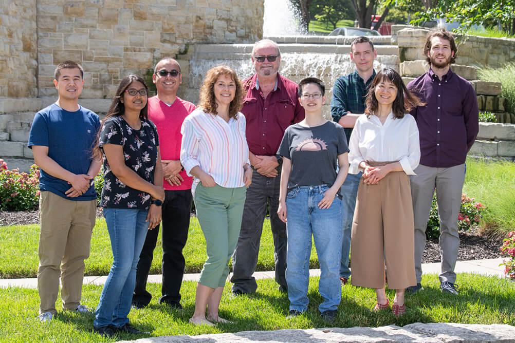 Dr. Jerry Workman's lab team standing in front of a fountain at the Stowers Institute in Kansas City